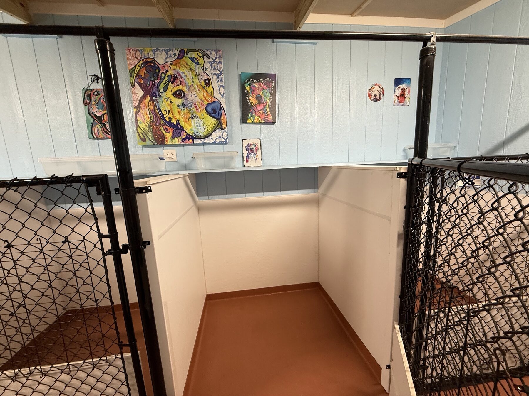 One of the indoor sleeping spaces, walled on three sides with a solid floor and dog artwork on the wall above